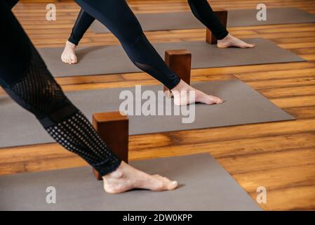 Femmes pratiquant l'étirement du yoga en utilisant des blocs de bois avec les mains, exercice pour la flexibilité de la colonne vertébrale et des épaules Banque D'Images