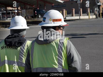 Deux travailleurs de l'électricité portant un casque de sécurité à bord complet marchent pour travailler à Santa Fe, Nouveau-Mexique. Banque D'Images