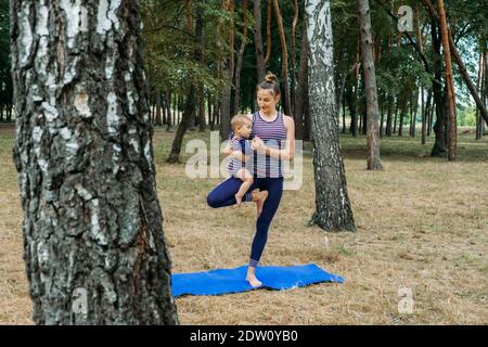 Salle de sport ou cours d'exercice en extérieur. La famille reste en forme en s'entraînant ensemble dans les parcs. Mère pratiquant le yoga avec sa fille tottdler bébé dans le Banque D'Images