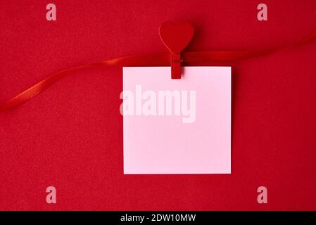 Arrière-plan de la Saint-Valentin. Feuille de papier vide avec ruban de fête sur fond rouge. Concept de la Saint-Valentin Banque D'Images