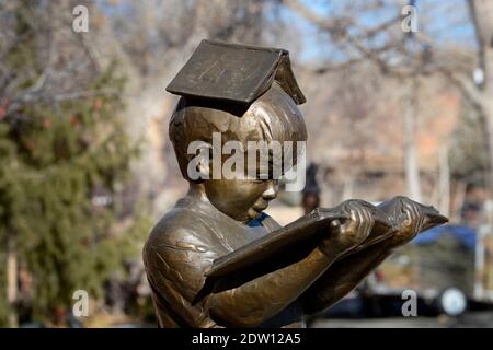 Une sculpture en bronze de Gary Lee Price d'un jeune garçon lisant un livre à l'extérieur d'une galerie d'art à Santa Fe, Nouveau-Mexique. Banque D'Images