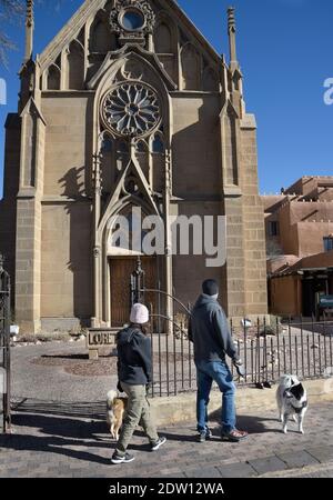 Un couple marche leurs chiens devant la chapelle historique de Loretto construite à Santa Fe, Nouveau-Mexique, en 1878. L'ancienne église catholique romaine est maintenant un musée. Banque D'Images