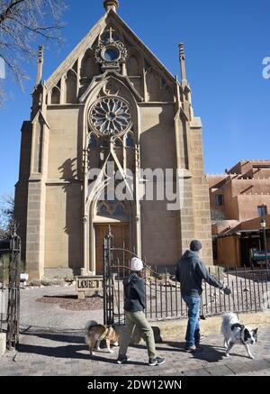 Un couple marche leurs chiens devant la chapelle historique de Loretto construite à Santa Fe, Nouveau-Mexique, en 1878. L'ancienne église catholique romaine est maintenant un musée. Banque D'Images