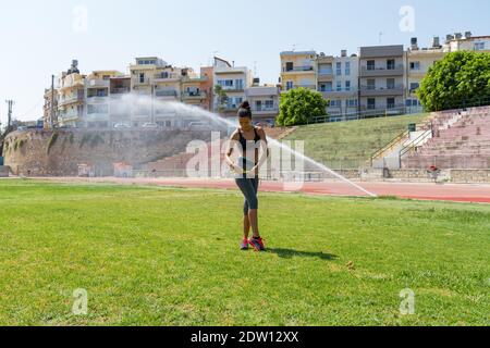 Athlète féminine arrosée d'eau dans des vêtements de sport mesurant la taille Banque D'Images