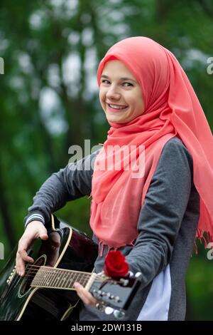 Portrait de la bonne fille musulmane essayant de jouer de la guitare Banque D'Images