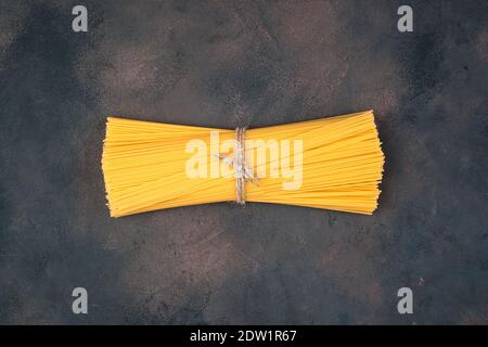 Longs spaghetti noués avec du fil sur un fond de béton brun. Banque D'Images