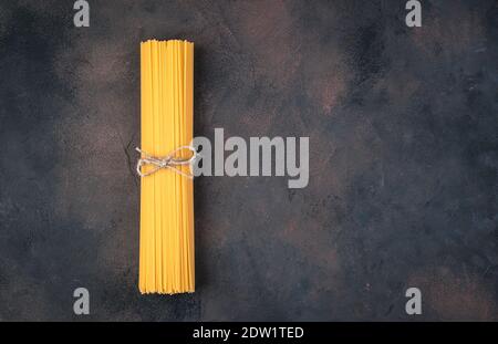 Spaghetti noués avec du fil sur un fond de béton brun. Banque D'Images