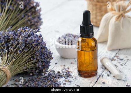 Bouteille compte-gouttes d'huile essentielle de lavande, sachets et bouquets de fleurs de lavande séchées. Banque D'Images