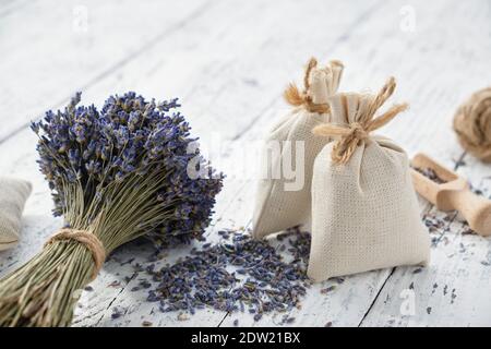 Bouquets de fleurs de lavande secs et sachets aromatiques sur table en bois blanc. Banque D'Images