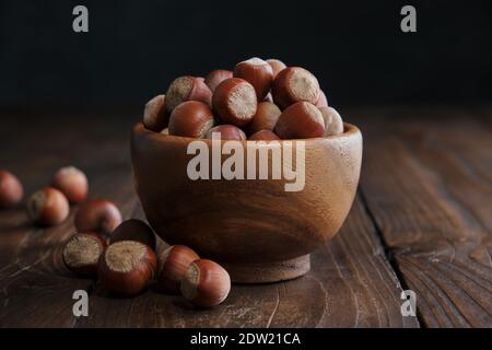 Bol en bois de noisettes sur une table en bois sombre. Banque D'Images