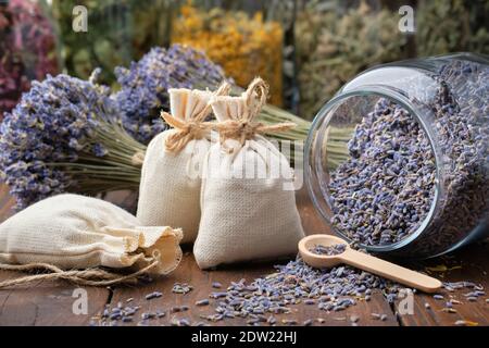 Pot en verre de fleurs de lavande sèches, sachets, petits pains de lavande sèche. Pots de différentes herbes médicinales sèches sur fond. Médecine alternative. Banque D'Images