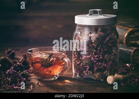 Tasse de thé d'échinacée saine, pot en verre d'herbes de coneflower sèches et de vieux livres sur la table. Banque D'Images