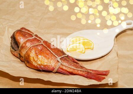 Bar chaud fumé au citron, gros plan sur le fond de papier froissé. Délicieux fruits de mer pour une bonne nutrition Banque D'Images