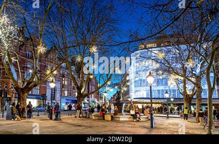 Personnes célébrant Noël à Sloane Square dans la nuit Londres Royaume-Uni Banque D'Images