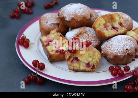 Muffins faits maison aux raisins de Corinthe rouges, saupoudrés de sucre en poudre, disposés sur fond sombre. Gros plan. Format horizontal Banque D'Images