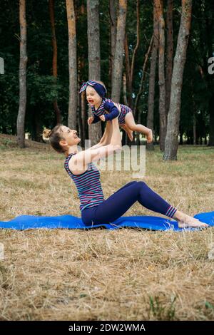 Salle de sport ou cours d'exercice en extérieur. La famille reste en forme en s'entraînant ensemble dans les parcs. Mère pratiquant le yoga avec sa fille tottdler bébé dans le Banque D'Images