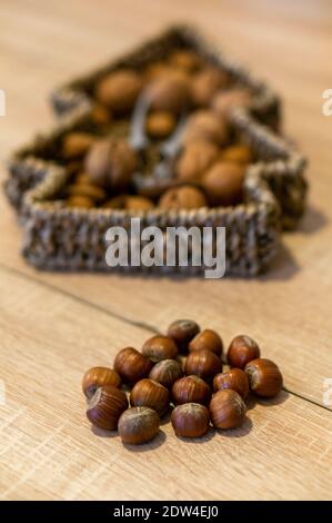 Un cliché sélectif d'un tas de noisettes, un panier tissé en forme d'arbre de Noël avec des noix mélangées en arrière-plan Banque D'Images