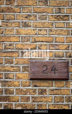 Une plaque en laine sur un mur de briques jaunes avec le numéro 24 Banque D'Images