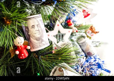 Des billets de dollar accrochés à un arbre de Noël et des décorations de Noël traditionnelles. Banque D'Images