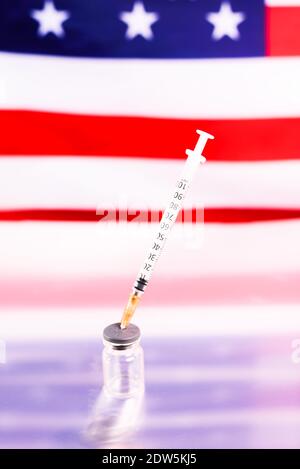 Flacons médicaux avec le vaccin Covid et une seringue, devant un drapeau américain non focalisé. Banque D'Images