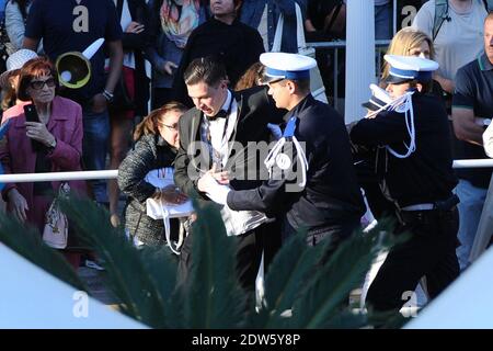 Le journaliste ukrainien Vitalii Sediuk envahit le tapis rouge en essayant de saisir la cheville de l'America Ferrera et est tenu par la sécurité lors de la projection du Dragon 2 au Palais des Festivals de Cannes, le 16 mai 2014, dans le cadre du 67ème Festival de Cannes. Photo d'Aurore Marechal/ABACAPRESS.COM Banque D'Images