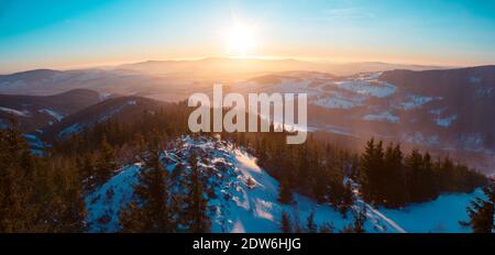 Vue panoramique sur les montagnes Eagle et Jesenik depuis le sommet de Kralicky Sneznik en hiver au coucher du soleil. La neige est couchée sur des collines avec beaucoup d'arbres. Banque D'Images