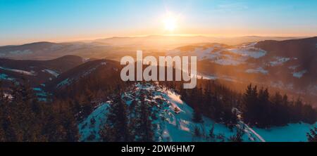 Vue panoramique sur les montagnes Eagle et Jesenik depuis le sommet de Kralicky Sneznik en hiver au coucher du soleil. La neige est couchée sur des collines avec beaucoup d'arbres. Banque D'Images