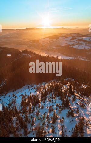 Vue panoramique sur les montagnes Eagle et Jesenik depuis le sommet de Kralicky Sneznik en hiver au coucher du soleil. La neige est couchée sur des collines avec beaucoup d'arbres. Banque D'Images