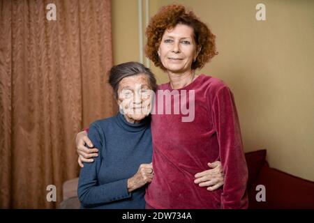 La fille adulte prend soin de la mère âgée souffrant de démence, la vieille femme quatre-vingt-dix ans cheveux gris et rides sur le visage et doux sourire, f Banque D'Images