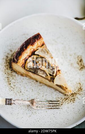 Morceau de cheesecake à la poire sans sucre végétalien sans lait dans une assiette rustique et poire fraîche sur fond de table en marbre blanc, mise au point sélective, gros plan. Mod Banque D'Images