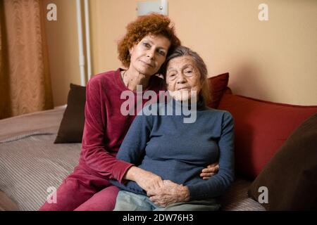 La fille adulte prend soin de la mère âgée souffrant de démence, la vieille femme quatre-vingt-dix ans cheveux gris et rides sur le visage et doux sourire, f Banque D'Images