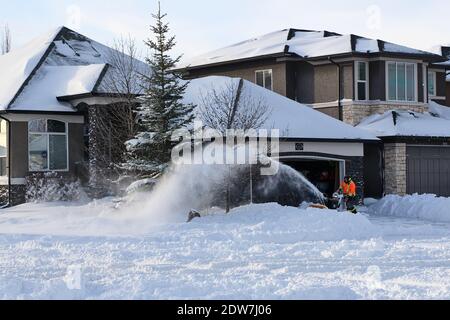 Personne utilisant une souffleuse à neige pour déneiger la route après 30 cm de neige, Calgary, Lake Chapala, Alberta, Canada : 2020-12-22 Banque D'Images