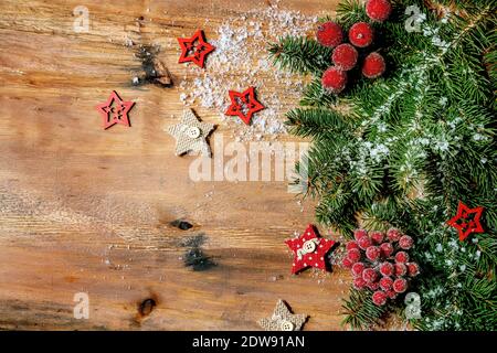 Noël nouvel an mise en page créative ou carte de vœux avec branches de sapin, baies rouges et étoiles sur fond de bois. Flat lay, espace de copie Banque D'Images