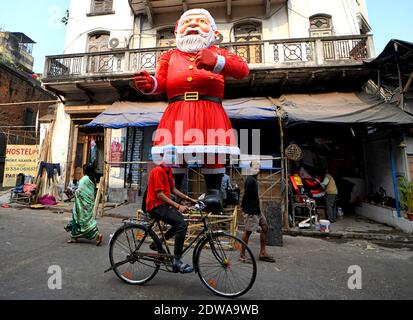 Kolkata, Inde. 22 décembre 2020. Un homme portant un masque et un masque passe devant un effigie géant de la Clause de Santa dans la rue. Crédit : SOPA Images Limited/Alamy Live News Banque D'Images