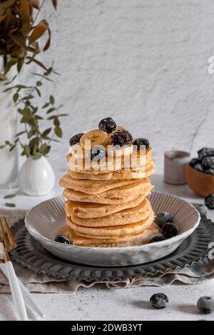 Une pile de crêpes de blé entier sans lait, servies avec du miel, de la banane et des baies Banque D'Images