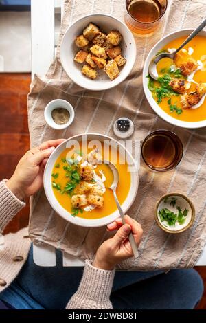 Une femme mange de la soupe de courge musquée dans un bol. Banque D'Images