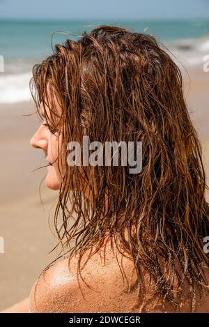Portrait d'une femme en profil avec un regard réfléchi et de longs cheveux, fond de mer, de près Banque D'Images