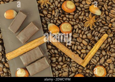 Grains de café et noix avec cannelle comme arrière-plan. Grains de café et anis dispersés sur une table avec des noisettes et de la cannelle comme papier peint ou backgroun Banque D'Images