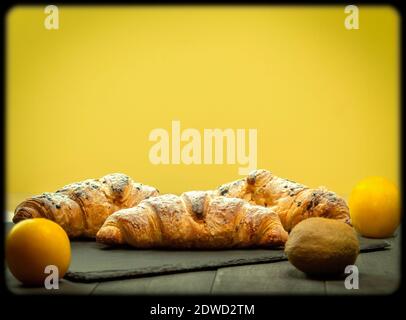 Croissant avec garniture de fruits comme fond. Croissant frais et croustillant sur un plateau en pierre. Vue latérale Banque D'Images