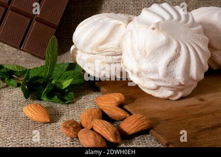 zephyr blanc, amandes pelées, bâton de chocolat noir et un petit bouquet de menthe fraîche couché sur un sac de toile et de bois vieilli Banque D'Images