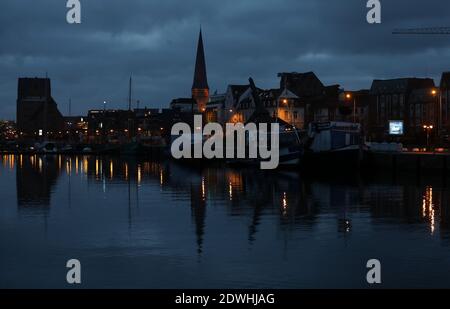 Rostock, Allemagne. 23 décembre 2020. Les lumières se reflètent dans l'eau du port de la ville en début de matinée. Les vacanciers et les touristes ne sont plus autorisés sur la mer Baltique depuis le début du second confinement, les Hanseatic fêteront Noël et le nouvel an chez eux et entre eux. Credit: Bernd Wüstneck/dpa-Zentralbild/ZB/dpa/Alay Live News Banque D'Images