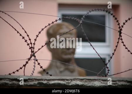 Un buste en bronze du fondateur de la Turquie Mustafa Kemal Atatürk derrière le fil barbelé devant le mur d'un bâtiment scolaire. Symbole de la suppression de Kem Banque D'Images