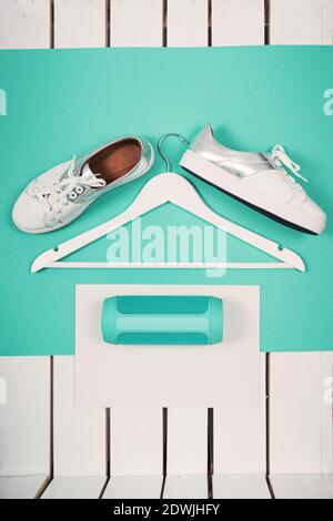 Chaussures de sport blanches modernes à poser pour Femme. Photographie avec vue sur le dessus du toit. Concept de style de vie des jeunes. Taille carrée. Fond turquoise Banque D'Images