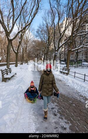 New York, États-Unis, décembre 2020. Les jeunes filles portent des masques avec leur traîneau dans l'Upper West Side, Manhattan, New York pendant la crise Covid. Banque D'Images