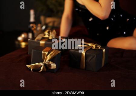 Femme avec des cadeaux dans des boîtes noires avec un ruban d'or. Gros plan Banque D'Images