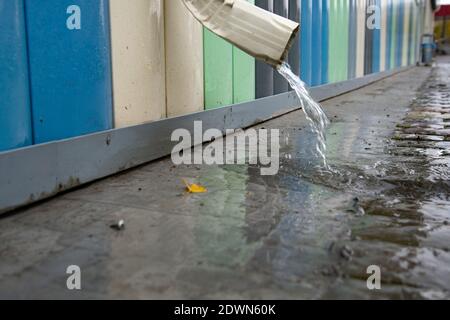 L'eau de pluie s'écoule du toit du bâtiment par un drain. Élimination de l'eau de pluie. Tuyau de descente blanc Banque D'Images