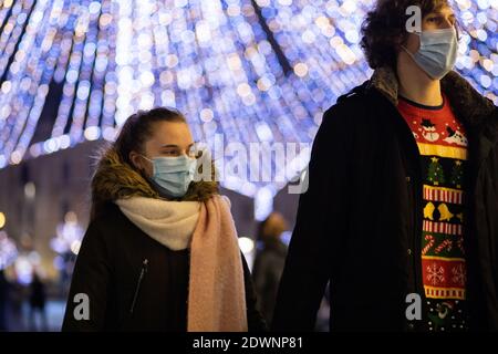 CLUJ-NAPOCA, ROUMANIE - 22 DÉCEMBRE 2020: Personnes portant un masque sur les lumières de Noël de rue Banque D'Images