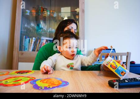 POZNAN, POLOGNE - 05 mars 2016 : une femme assise avec un enfant près d'une table jouant avec un puzzle de marque Banque D'Images