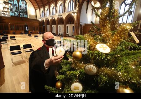 Le très Rév Dr Derek Browning ancien modérateur de l'Assemblée générale de l'Église d'Écosse avec l'arbre de Noël à l'intérieur de l'église paroissiale de Morningside, Édimbourg comme il fait la préparation pour les fidèles avant le service de jour de Noël. Banque D'Images