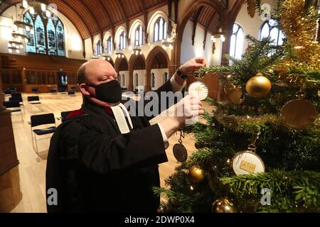 Le très Rév Dr Derek Browning ancien modérateur de l'Assemblée générale de l'Église d'Écosse avec l'arbre de Noël à l'intérieur de l'église paroissiale de Morningside, Édimbourg comme il fait la préparation pour les fidèles avant le service de jour de Noël. Banque D'Images